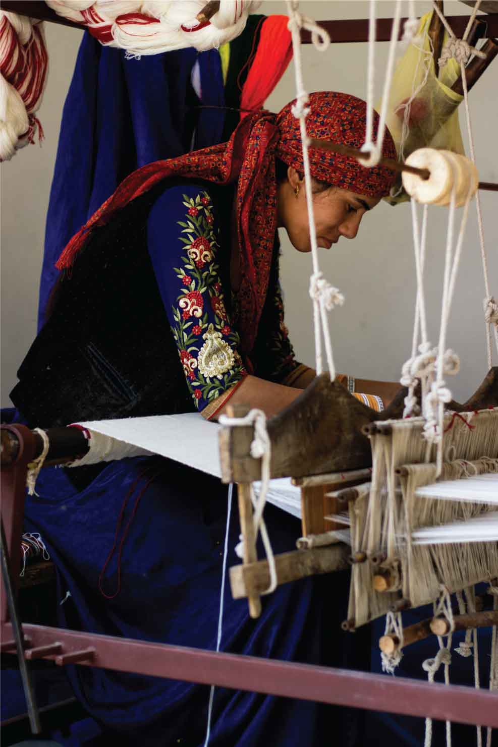 A lady using a weaving machine to weave the fabric